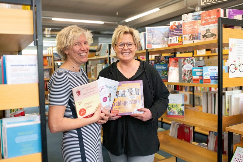 Die Leiterin der Hürther Stadtbücherei Barbara Hoevels (links im Bild) und ihre Mitarbeiterin Sabine Wingen präsentieren einen Teil der gespendeten Produkte.