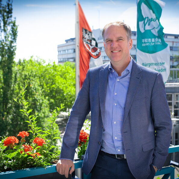 Bürgermeister Dirk Breuer mit der „Mayors for Peace“-Flagge vor dem Rathaus der Stadt Hürth.